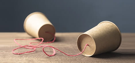 Stark image of paper cup telephone, cups joined by string